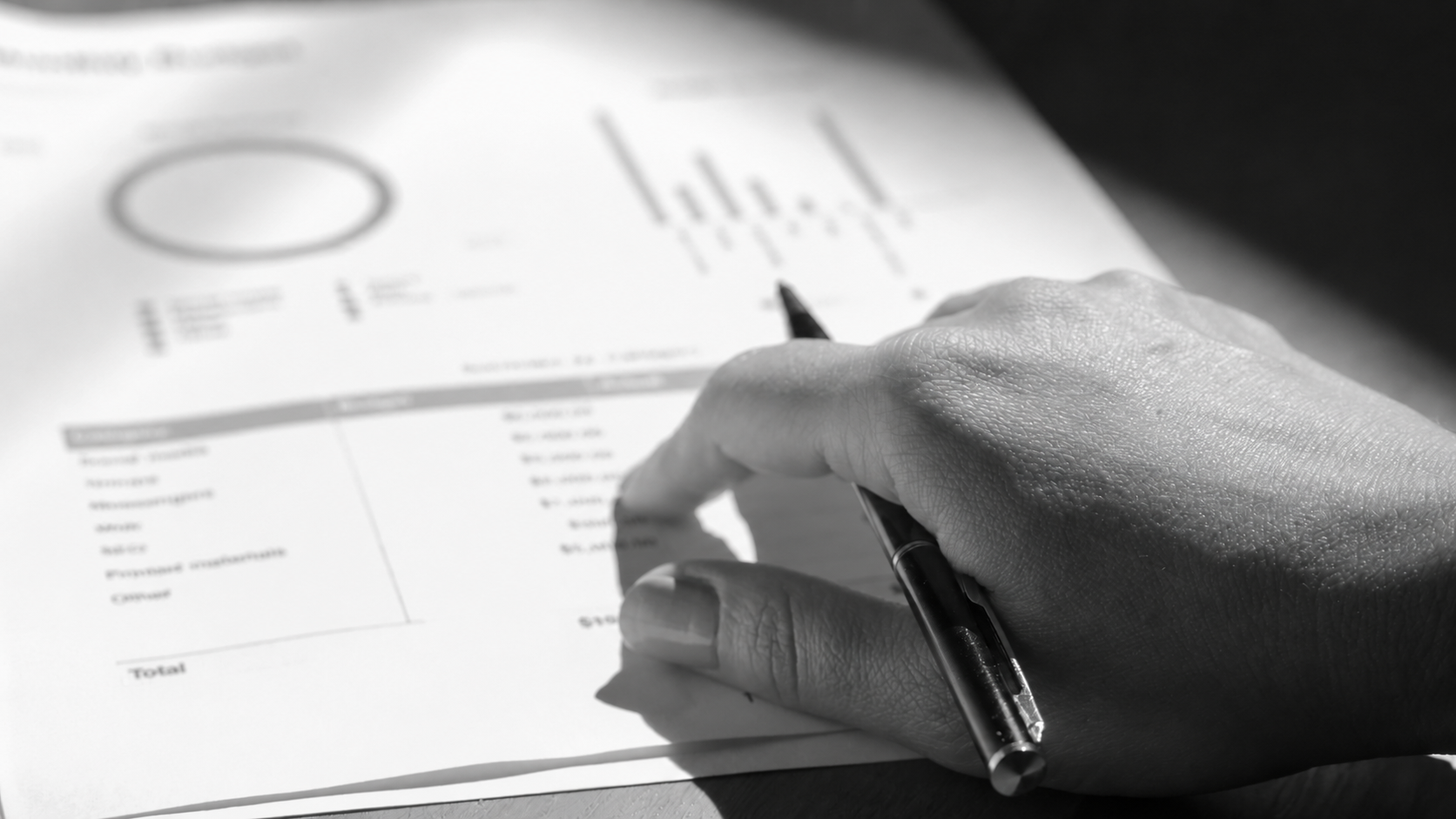 Hand with a pen analysing charts in a report