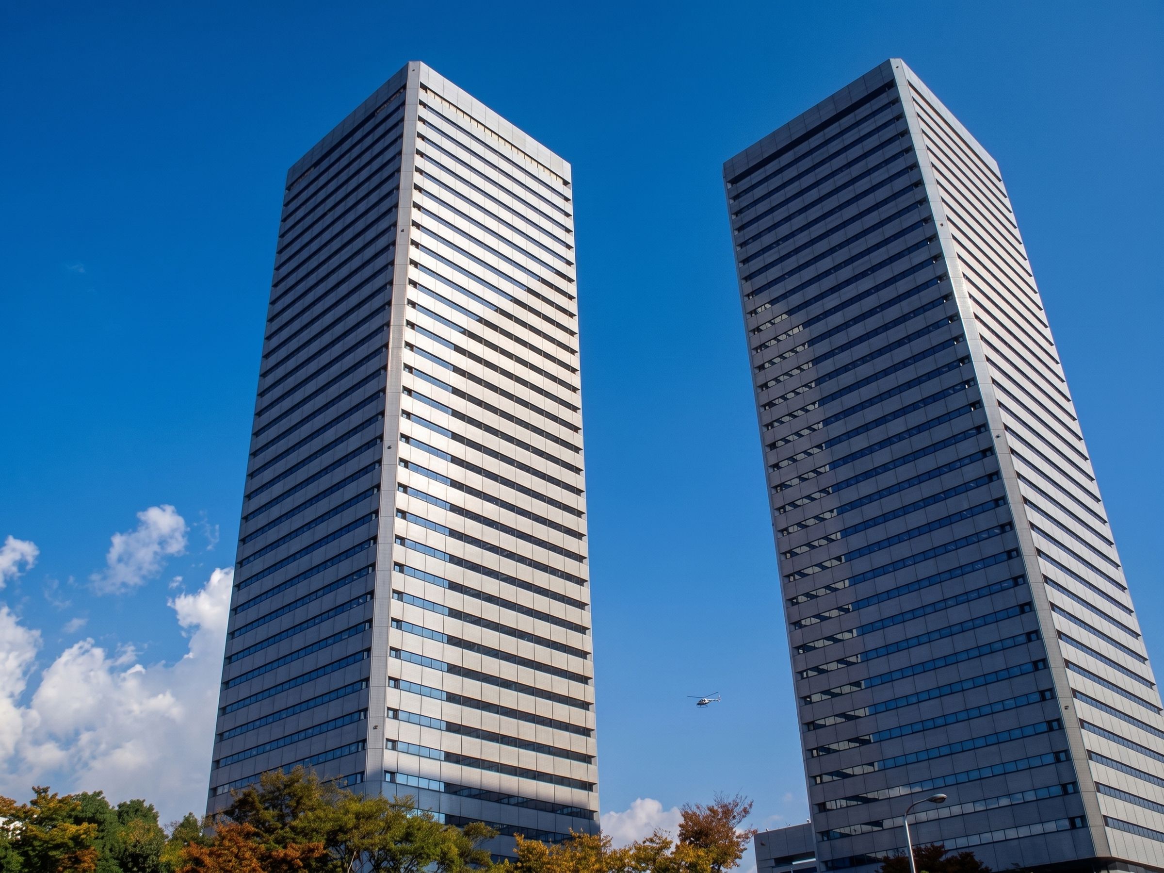 Two similar office towers rising side by side against a clear blue sky