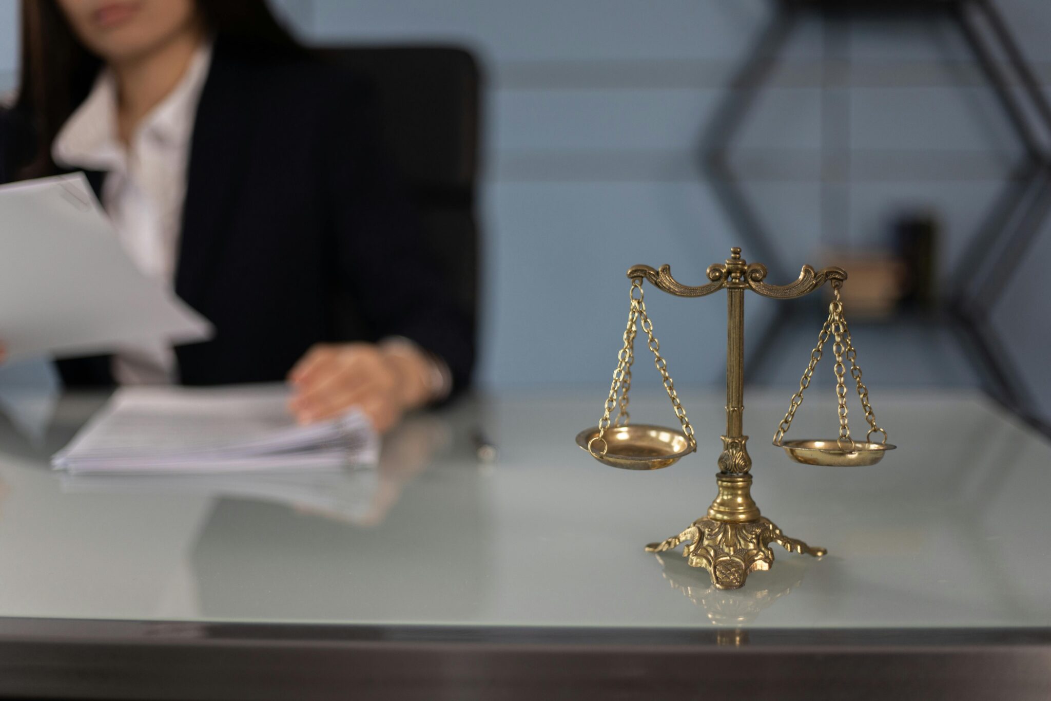 Scales of justice on a desk beside a person reviewing documents
