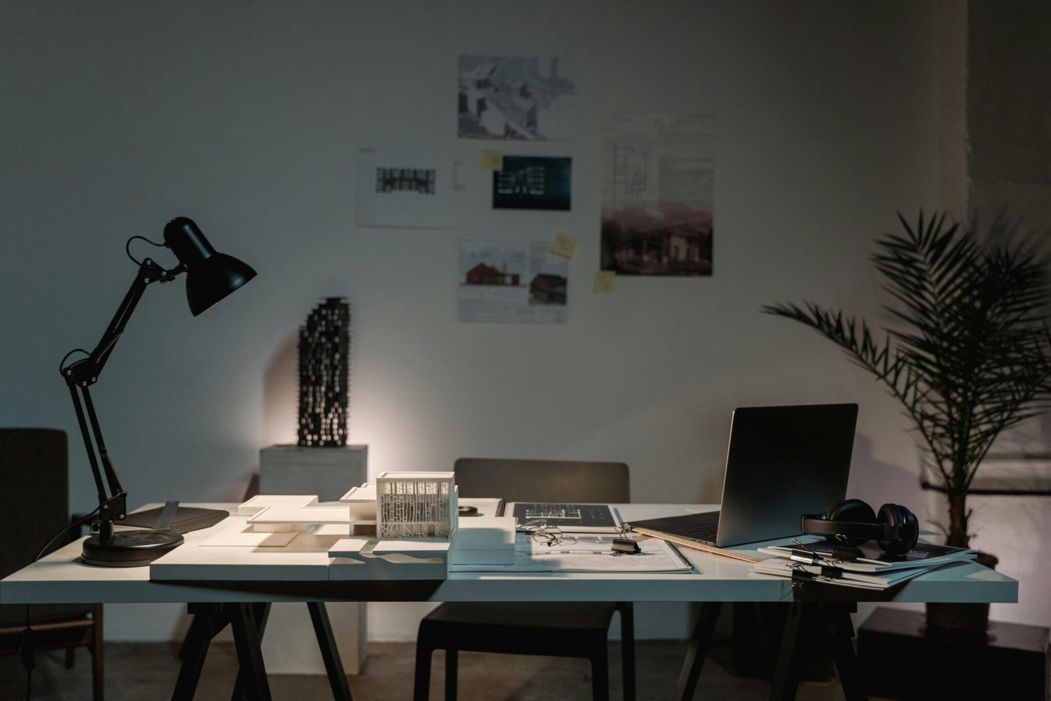 Home office desk with a lamp, laptop and plans