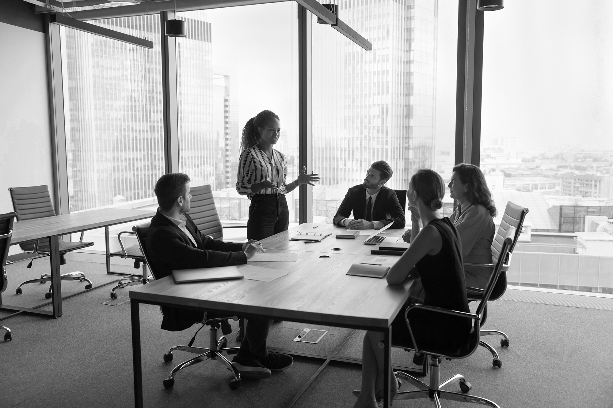 Presenter leading a meeting in a boardroom with city views