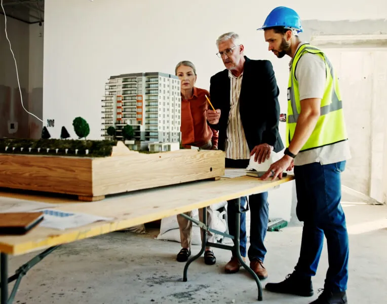 Project team in hard hats reviewing a building model on a construction site