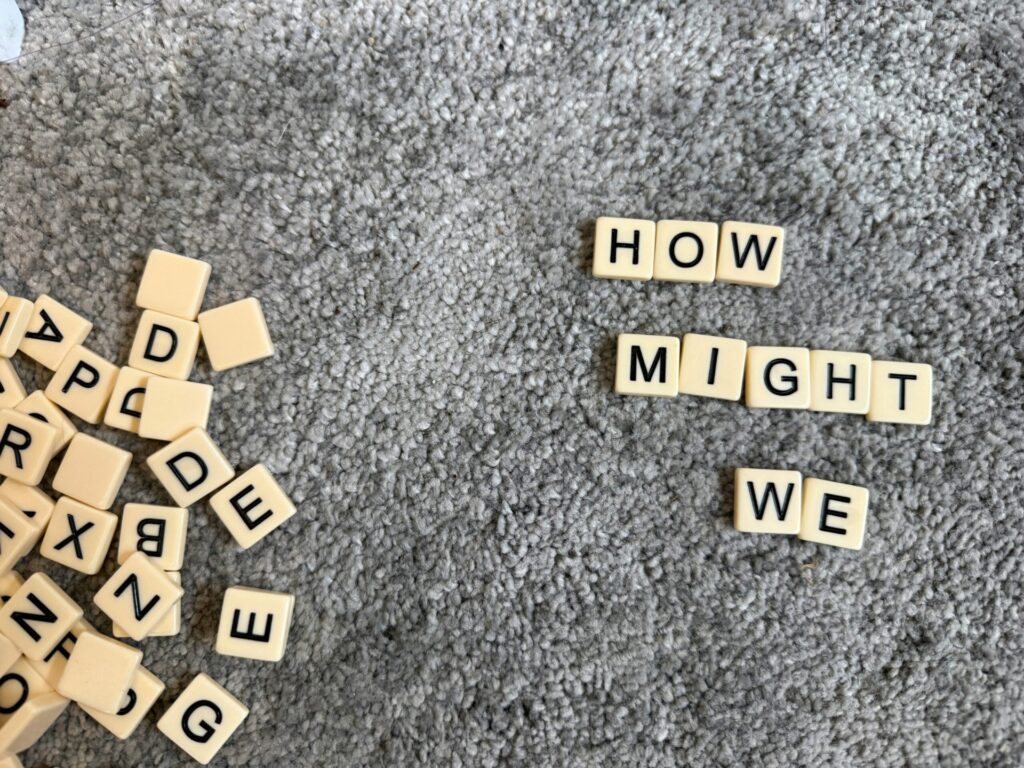 Letter tiles spelling 'how might we'